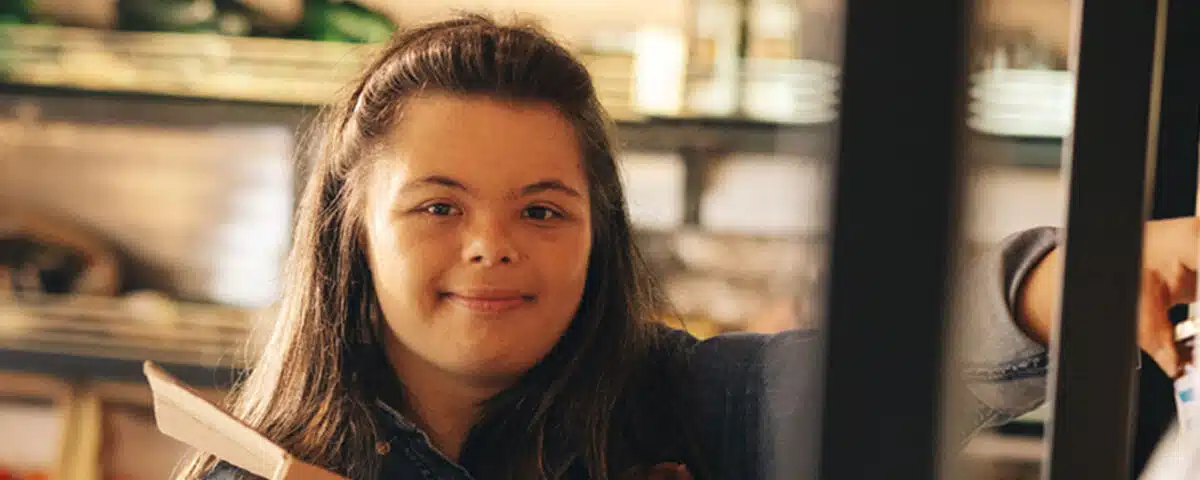 Convenience store employee with Down syndrome restocking food products